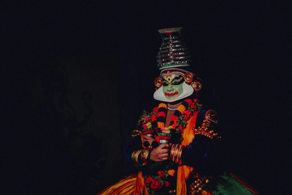pexels-photo-20258867-20258867 Colorful traditional Kathakali dancer with a distinctive mask on a black background.